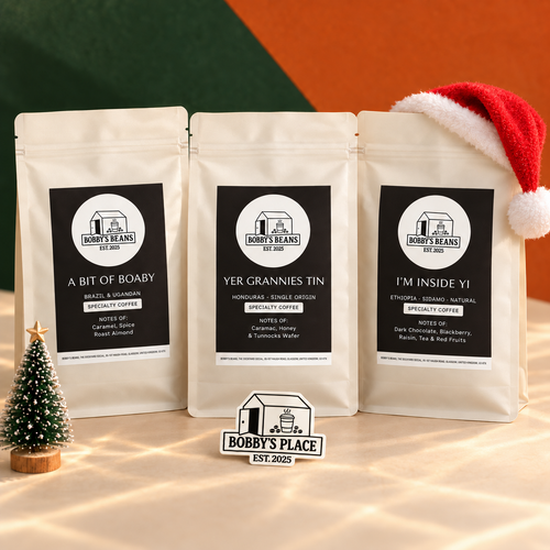 Taste of Bobby's Trio with A Bit of Boaby, Yer Grannies Tin and I'm Inside Yi coffee bags, styled with a Santa hat and miniature Christmas tree. Includes a Bobby's Place glow in the dark sticker.